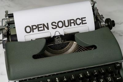 A green type writer with a printed sheet saying Open Source
